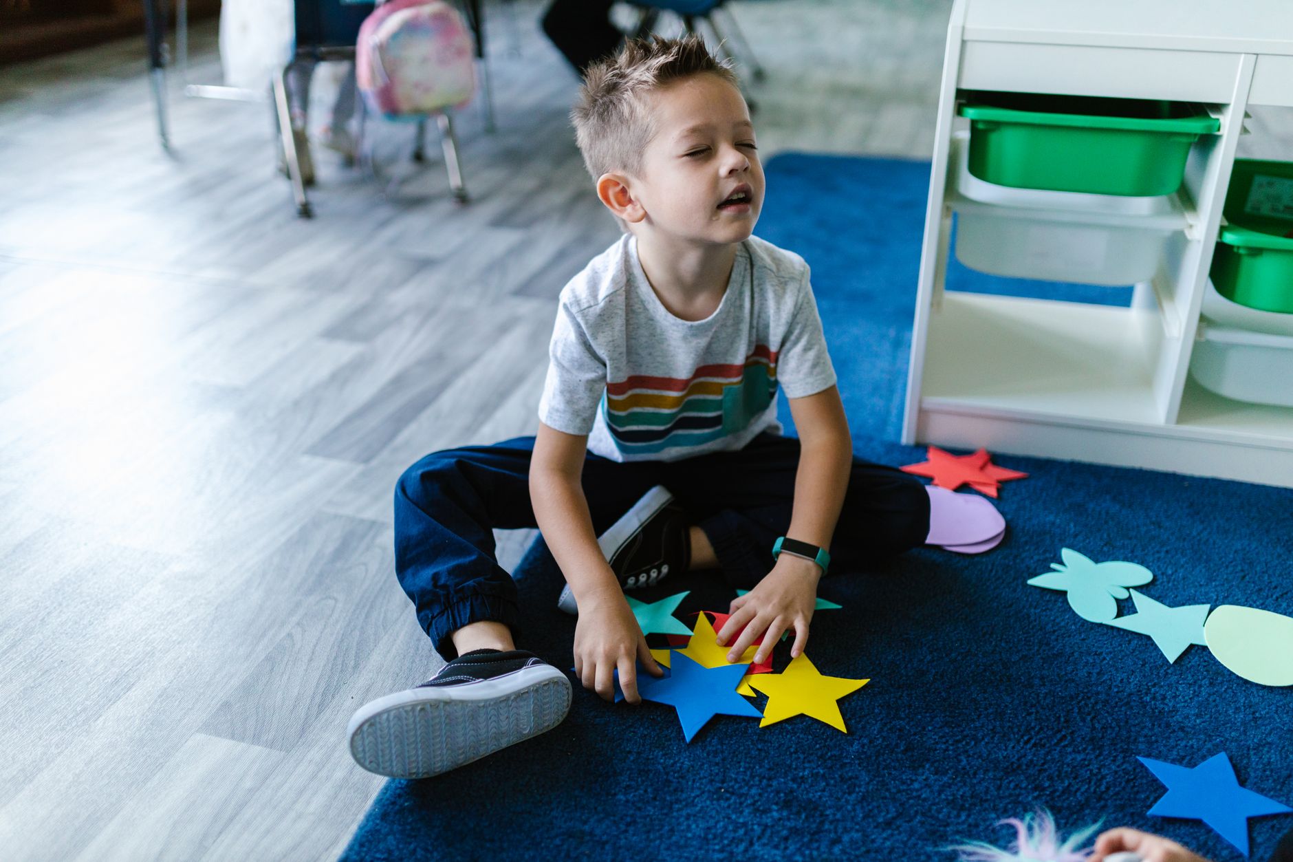 Dijete slaže papirnate zvjezdice na tepihu u jasličkoj sobi